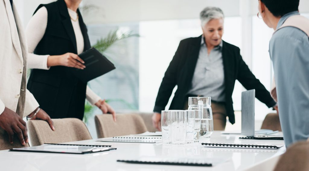 Business people sitting down to a redundancy meeting around a board room table