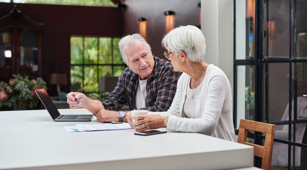 Man and woman sitting at kitchen counter with laptop and paperwork considering an electronic will