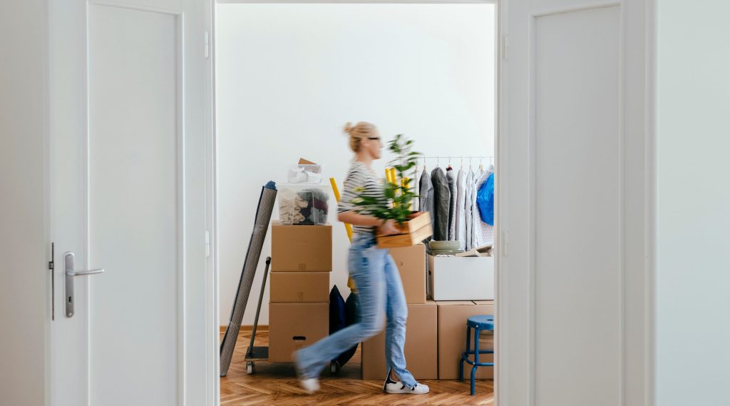 Lady walking past open doorway carrying moving boxes after the matrimonialisation of her property